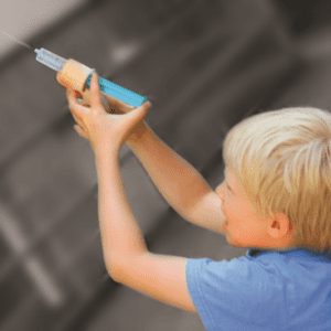 kind speelt met houten waterpistool en spuitje